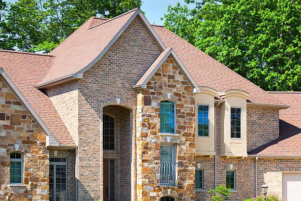 A sizable house with asphalt shingle roofing and a large driveway, showcasing a car parked in front.