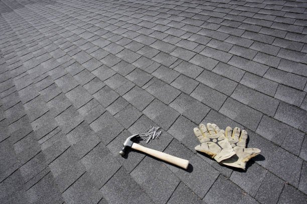 A hammer and a pair of gloves resting on a roof, suggesting preparation for roofing work.