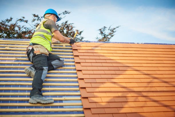 A roofing contractor in South Bend, IN climbing a ladder for roof replacement, wearing safety gear and focused on the task.