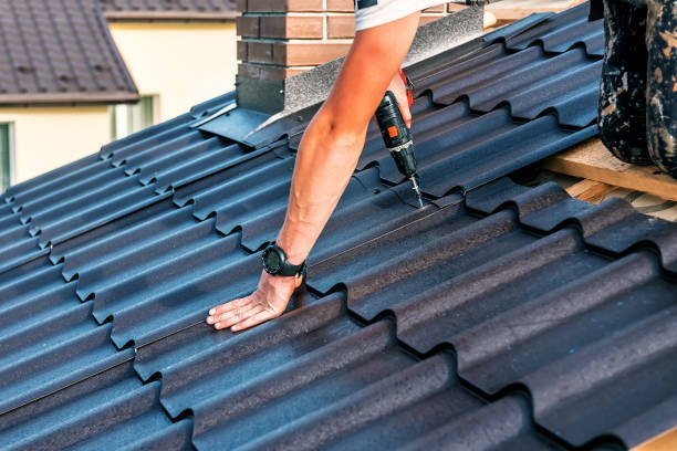 A roofer performing urgent roof repair on a storm-damaged metal roof, showcasing emergency response and safety measures.