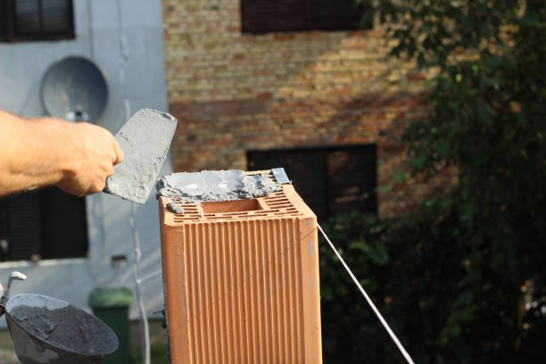 A man repairs a brick chimney, focusing on fixing leaks to ensure proper functionality and safety.