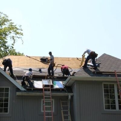 A group of men collaborating on a roof installation project, using tools and materials for construction.