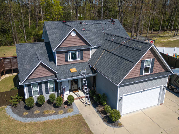 Two men installing a roof on a house, focused on their work and using safety equipment.