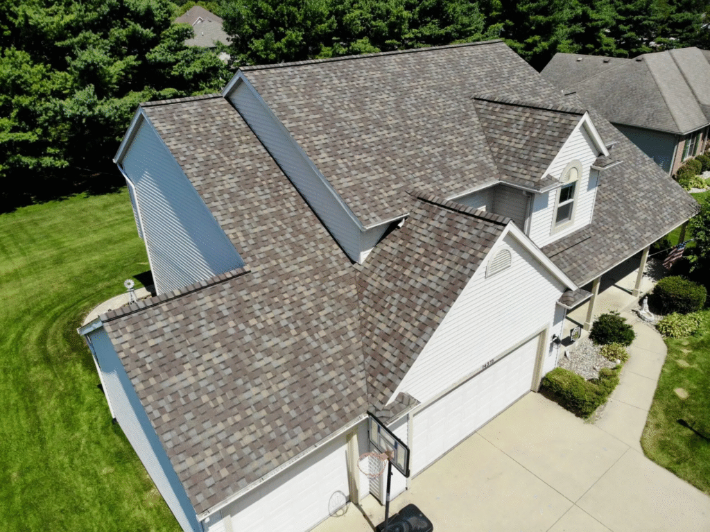 Two men working together on a house roof, engaged in roof installation tasks.