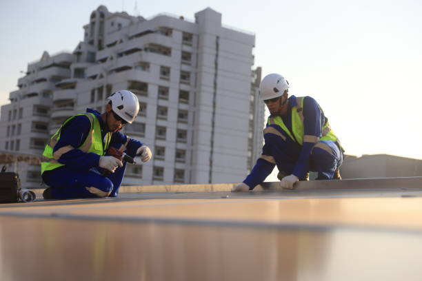Two men working together on a house roof to address a leak repair using drill and other tools.