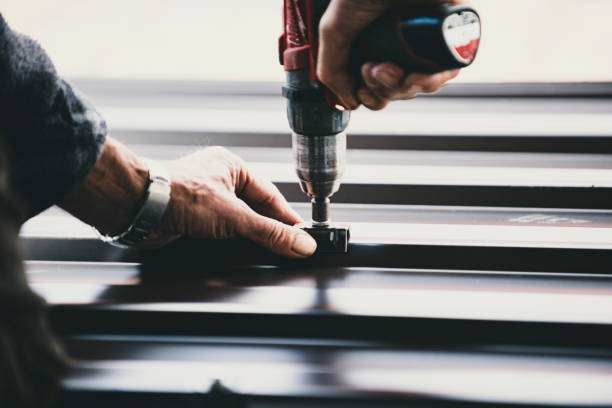 A man uses a drill to secure a metal roof, showcasing the installation of metal roofing.
