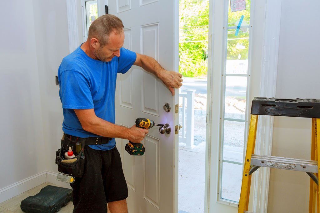A man performing door replacement using a drill, focused on the task in a home improvement setting.