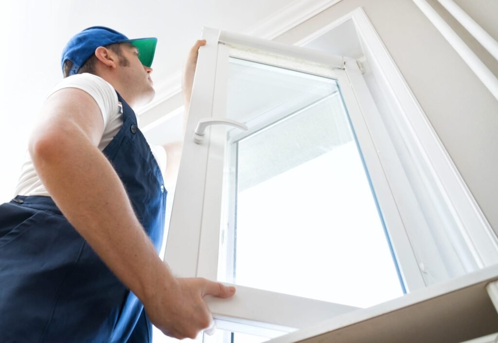 A man in overalls performing window installation, focused on fixing the frame and ensuring a proper fit.