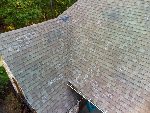 local roofer Goshen repairing damaged roof shingles on residential house