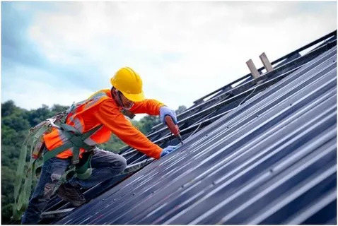 Roofing crew working on a steep roof structure performing expert commercial roof replacement services